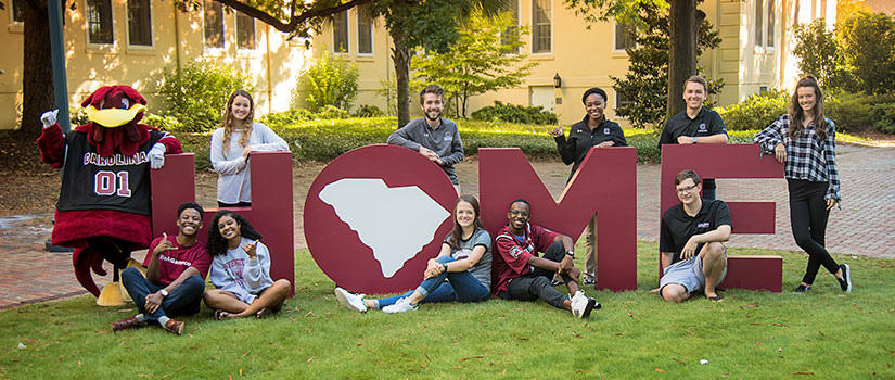 group of students posing in front of "HOME" letters