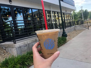 Photo of an iced coffee in front of the Sweetwaters Coffee Shop