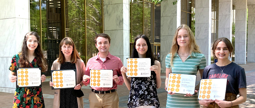 Students hold award certificates outside Thomas Cooper Library