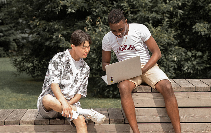 students on a bench using a laptop
