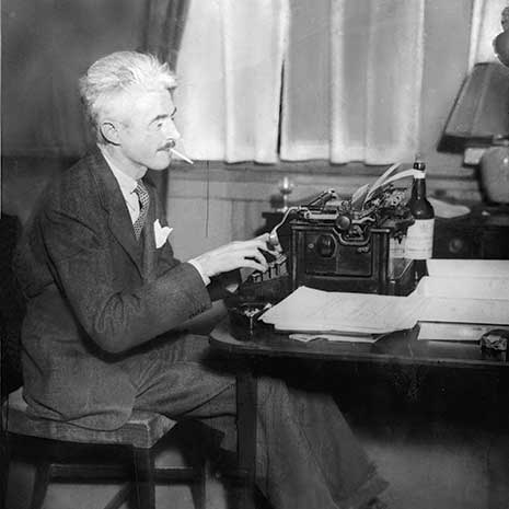 a black and white photo of Dashiell Hammett at a typewriter