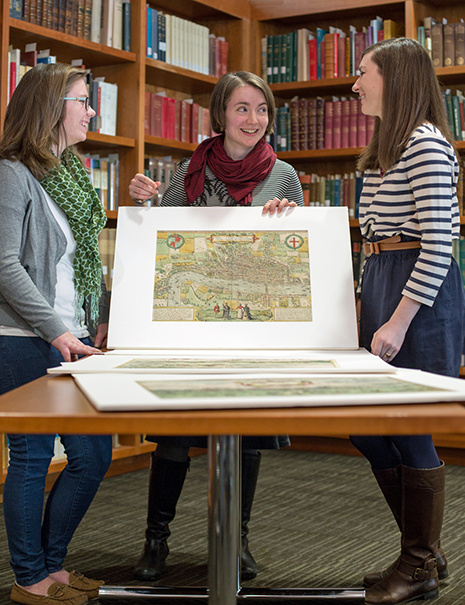 Professor Jeanne Britton shows two students maps from the John and Mary Osman Braun and Hogenberg Collection 