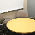 round table with two chairs and edge of a white board