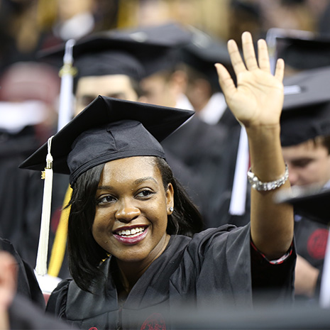 student at graduation waving