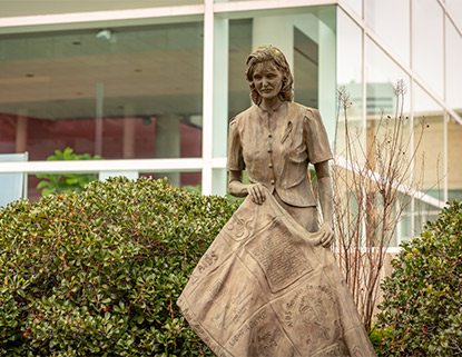 Statue of a woman holding a quilt in front of the Koger Center for the Arts. 