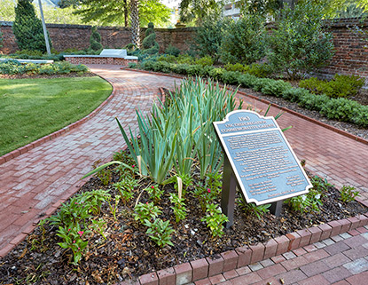 Desegregation Garden featuring brick walkways, green grass and flowers and a plaque. 