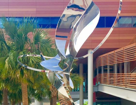 Metal sculpture in the Darla Moore School of Business courtyard surrounded by palmetto trees. 