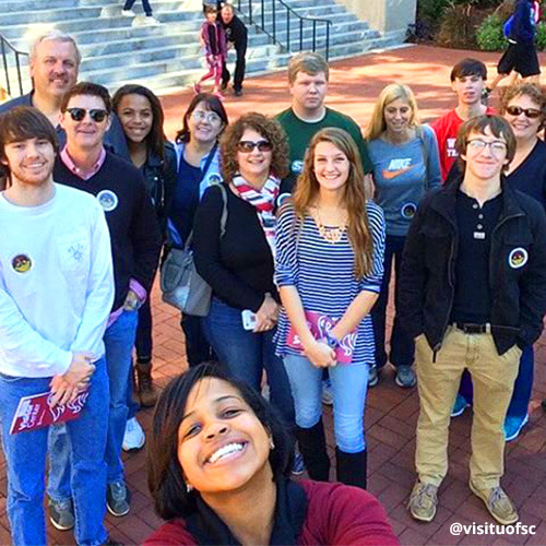 Tour guide smiles for a selfie with her group of prospective students/parents.