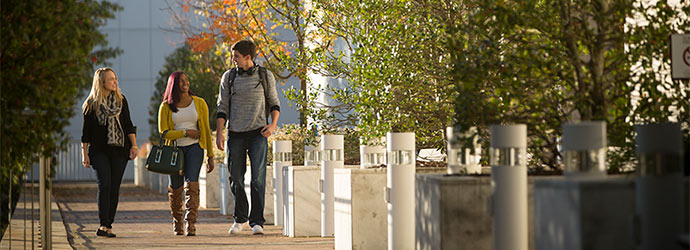 Three students walking outside the Thomas Cooper Library on a pretty fall day.