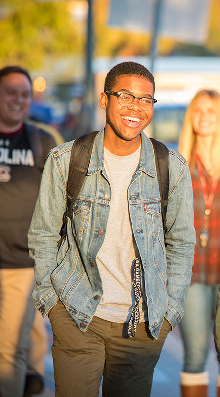 A student laughing while walking down the sidewalk.
