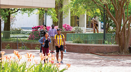 Two students walking through a patio on a beautiful spring day.