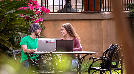 Two students studying at an outdoor table on a spring day.