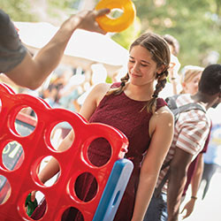 Student playing a large game of Connect Four at an outdoor event on Greene Street.