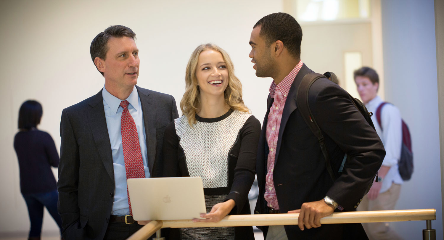 Three business professionals walking down a hallway.