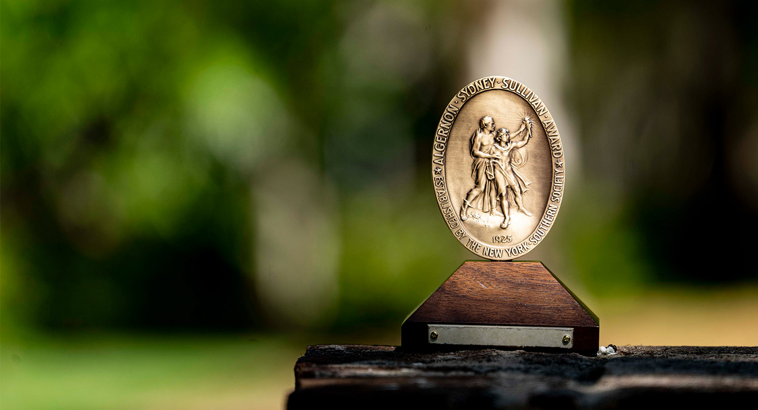The bronze Algernon Sydney Sullivan award sits on an outdoor wooden table.