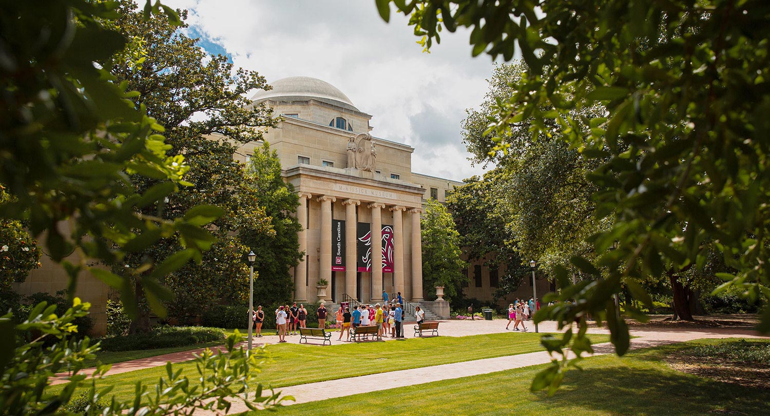 A tour leaving the steps of McKissick Museum surrounded by beautiful lush trees of the historic Horseshoe. 