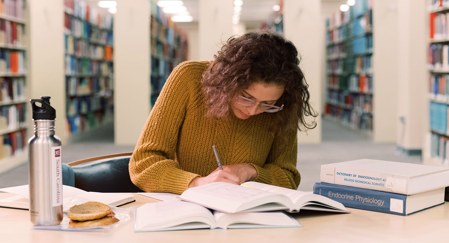 Student leaned over a table studying in the library.