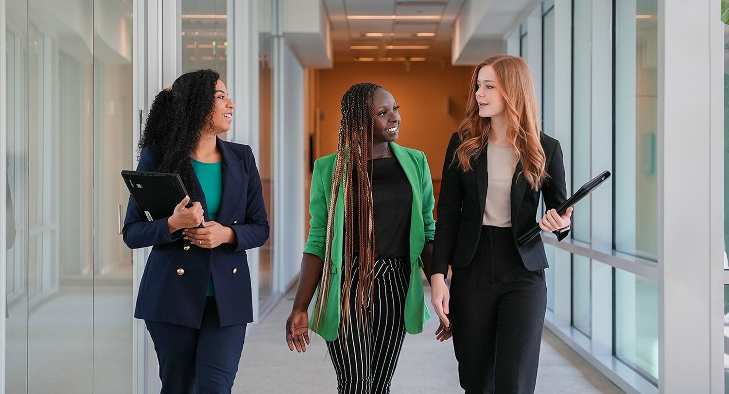 Three business professionals walking down a hallway.