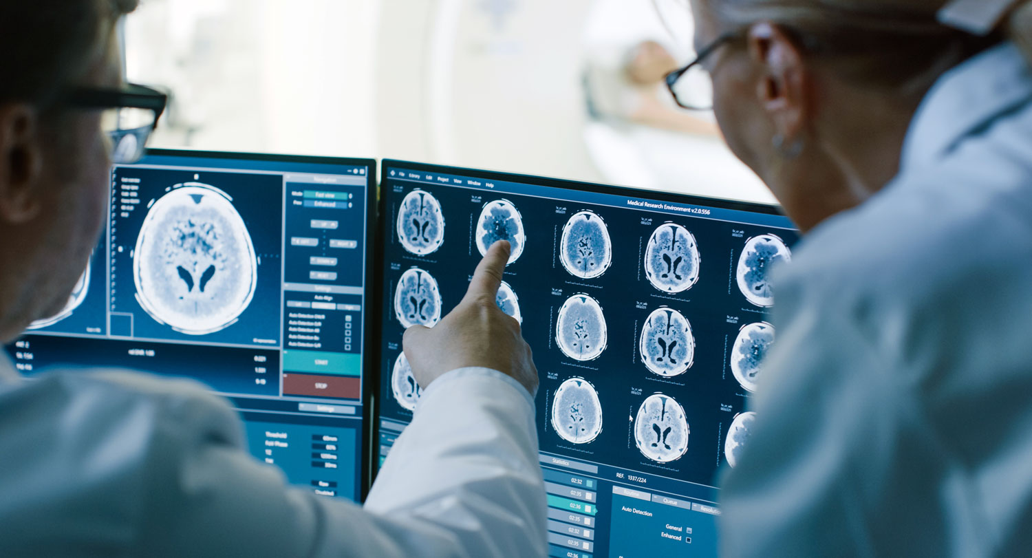 Medical professionals analyzing detailed brain MRI images on a diagnostic workstation, reviewing potential signs of neurological disease.