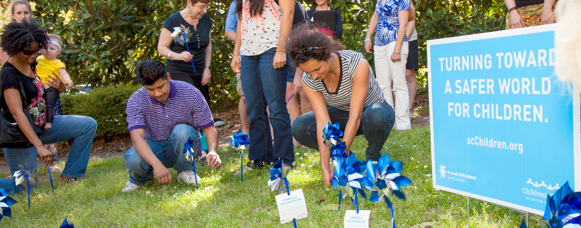 a group of students advocating for children with a display of blue pinwheels