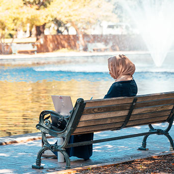 Student sitting on a bench near the reflecting pool.