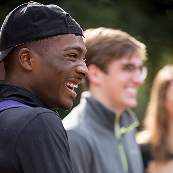 Two students laughing while standing outside on campus.