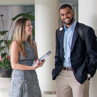 Two business professionals talking in a hallway.