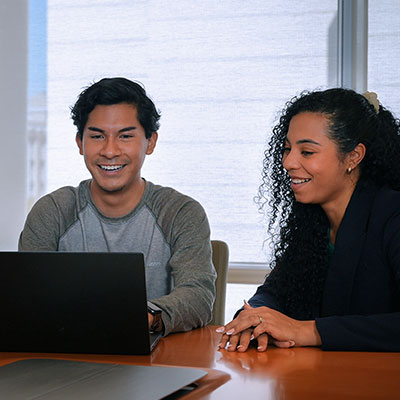 Two business professionals with a laptop at a conference table.