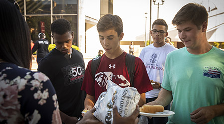 Students receiving hamburgers and hot dogs at a welcome week cookout