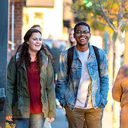 Students laughing with each other walking down the sidewalk.