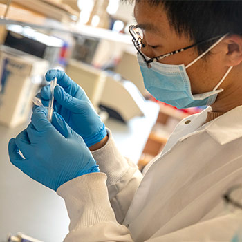 Student working in a lab wearing safty goggles and a mask.