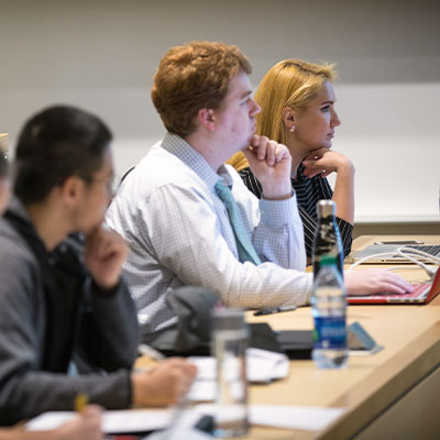 Students sitting at a row of desks in a classroom.