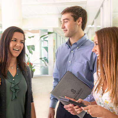 Three business students talking together in a hallway. 