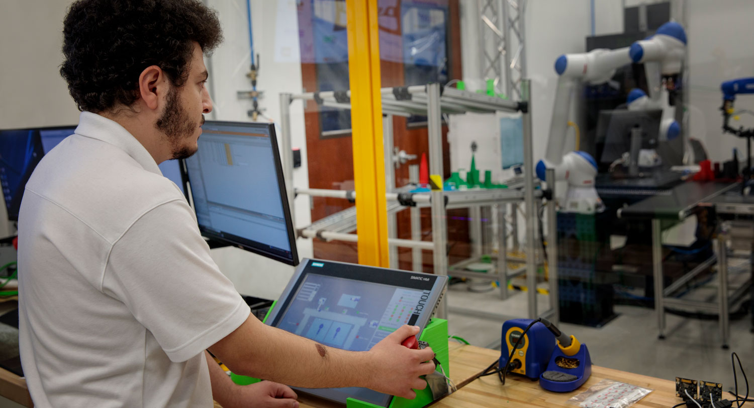 An engineering student woks on automated machinery in a lab 