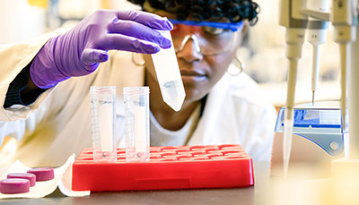 Researcher looking at a test tube at eye level.