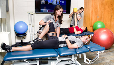 Students practicing physical therapy exercises on student volunteers in therapy classroom