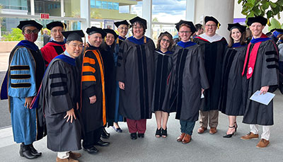 Group of alumni and faculty in graduation regalia at a commencement ceremony.