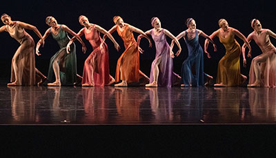 Group of dance students in a line in full costume during a performance on stage. 