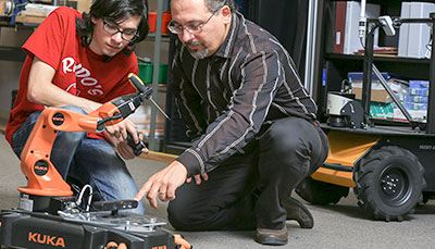 Student and faculty member looking at a machine. 