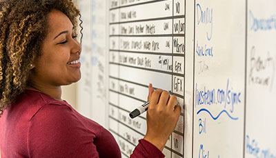 Student filling in a table on a whiteboard.