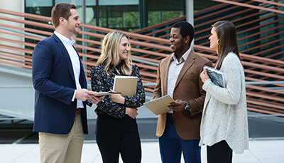 Group of business student standing outside in the Moore School courtyard.