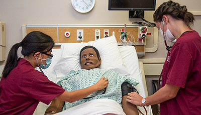 Two students practicing on a nursing manikin in the patient simulation lab 