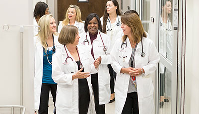 Group of doctors, nurses and administrators walking down the hallway in a hospital. 