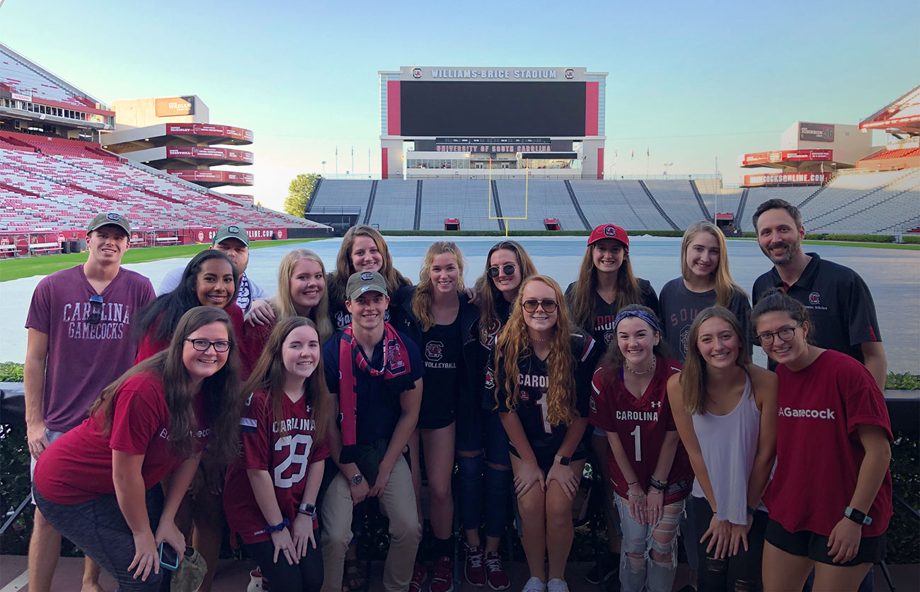 A University 101 class poses for a photo on the sidelines of the Williams Brice Stadium football field.