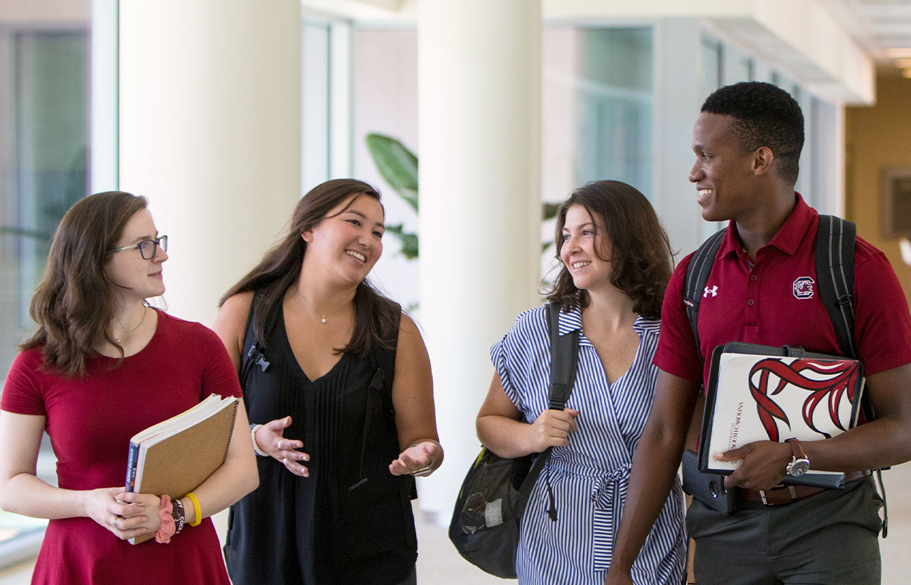 Group of students walking down the hall way of the Moore School building.