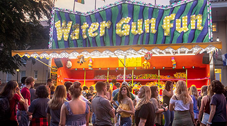 A water gun game carnival truck with studnets gathered around ready to play. 