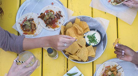 A view of a table of Mexican food including chips and queso and tacos.