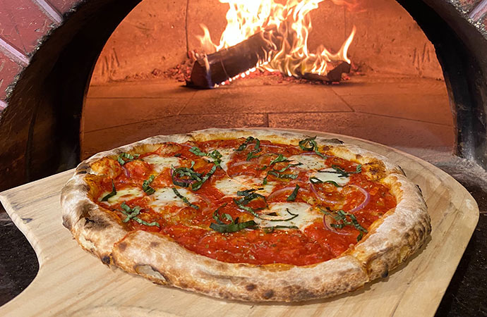 A pizza just coming out of a wood fire oven at Il Focolare Pizzeria.