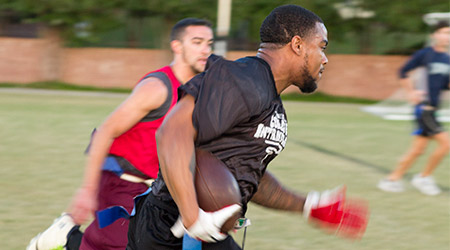 Students running with the ball while playing flag football.