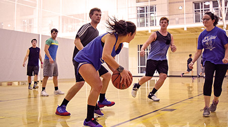 Co-ed basketball playing on a court at the wellness center. 
